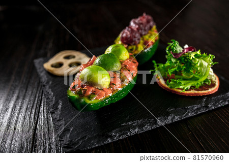 Salmon tartare and avocado salad on a black background Salmon tartare and avocado salad on a black background 81570960