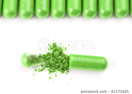 row of ufo green color organic capsules isolated on white background closeup with one opened 81572685