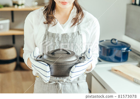 一個女人在廚房裡戴著手套，雙手拿著一個鍋 女人廚房 81573078