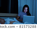 Woman sitting on bed in the night and using laptop computer 81573288