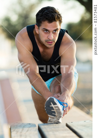 Male athlete stretching legs 81573481