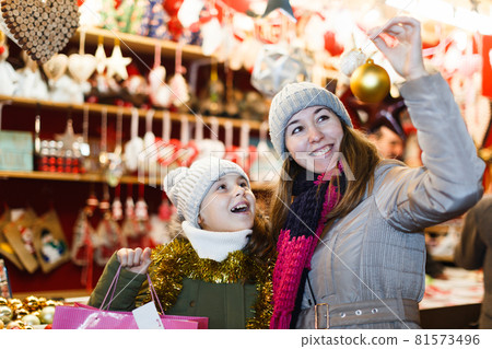 Young girl and her mother are choosing decorations for Christmas tree 81573496