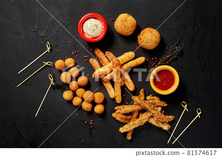 Allsorts of fried snacks with two different sauces on black background. Close-up. Top view 81574617