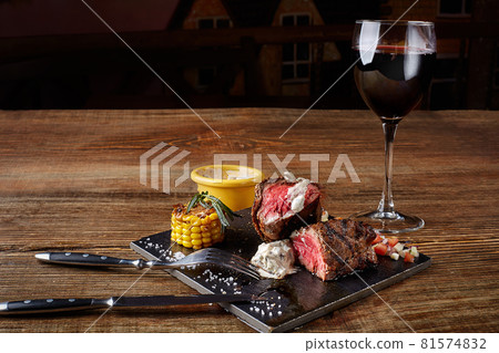 Barbecue steak with a glass of red wine as close-up on black board on wooden background 81574832