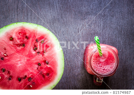 Watermelon smoothie and a half of fresh watermelon on dark wooden background. Flat lay or top view. Watermelon smoothie and a half of fresh watermelon on dark wooden background. Flat lay or top view. 81574987