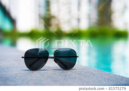 Sunglasses at the edge of the pool. Vacation concept close up Sunglasses at the edge of the pool. Vacation concept close up 81575279