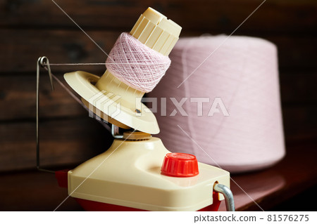 Mechanical yarn winder or reel while rewinding thread. Close-up, selective focus 81576275
