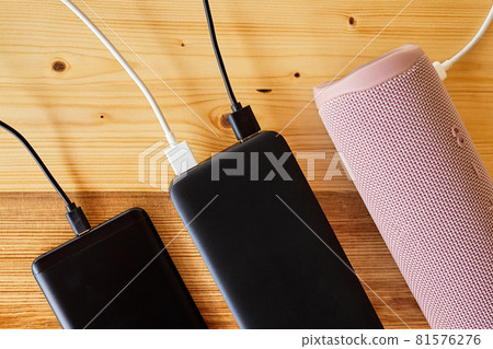 Powerbank charges smartphone and portable speaker using usb. Close-up, selective focus 81576276