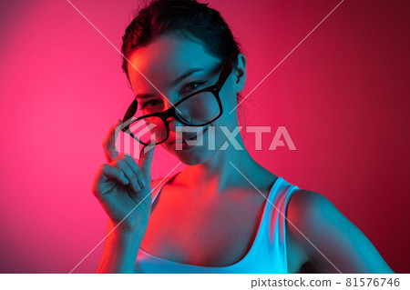 Girl boss. Cropped portrait of young beautiful girl in glasses on gradient pink red background Girl boss. Cropped portrait of young beautiful girl in glasses on gradient pink red background 81576746