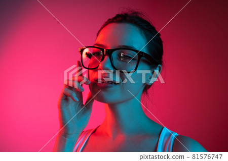 Cropped portrait of young beautiful girl in glasses on gradient pink red background Cropped portrait of young beautiful girl in glasses on gradient pink red background 81576747