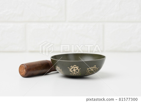 Tibetan singing copper bowl with a wooden clapper on a white wooden table, objects for meditation and alternative medicine Tibetan singing copper bowl with a wooden clapper on a white wooden table, objects for meditation and alternative medicine 81577300
