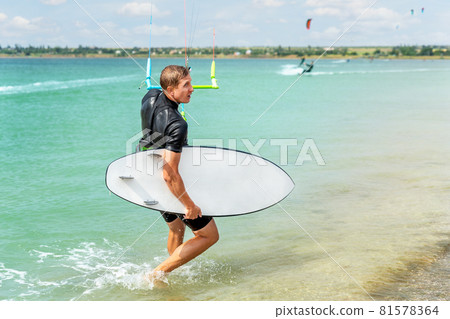 Back view of young adult caucasian fit male person enjoy riding kite surf board in sun uv protection suit on bright sunny day against blue sky at sea ocean shore. adrenaline fun adventure acitivity Back view of young adult caucasian fit male person enjoy riding kite surf board in sun uv protection suit on bright sunny day against blue sky at sea ocean shore. adrenaline fun adventure acitivity 81578364