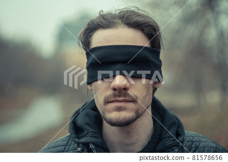 a man with a black blindfold over his eyes 81578656