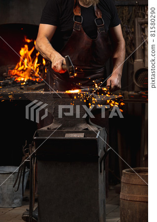 Cropped shot of man, blacksmith working on creating handmade metal product at family smithy. Concept of labor, retro professions, power, beauty Cropped shot of man, blacksmith working on creating handmade metal product at family smithy. Concept of labor, retro professions, power, beauty 81580290