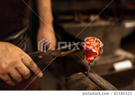 Beautiful rose. Blacksmith manually forging molten metal on anvil in smithy with spark fireworks. Concept of labor, retro professions, family business Beautiful rose. Blacksmith manually forging molten metal on anvil in smithy with spark fireworks. Concept of labor, retro professions, family business 81580323