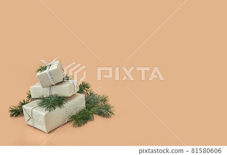 Christmas gift boxes and fir tree on beige background Christmas gift boxes and fir tree on beige background 81580606