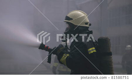 Fireman training with water hose 81580751
