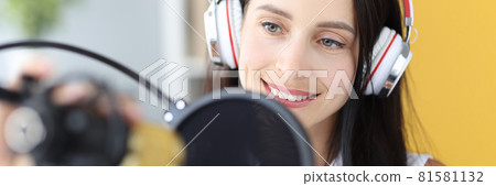 Portrait of young woman in headphones in front of microphone 81581132
