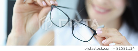 Young woman holds black glasses for vision in hands Young woman holds black glasses for vision in hands 81581134