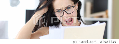 Young businesswoman looks at financial report in panic 81581135