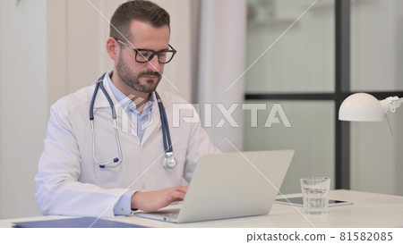 Middle Aged Doctor Working on Laptop in Hospital 81582085