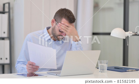 Middle Aged Man having Loss on Documents while Working on Laptop Middle Aged Man having Loss on Documents while Working on Laptop 81582195