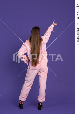 Back view. Full-length portrait of young long-haired woman isolated on purple background Back view. Full-length portrait of young long-haired woman isolated on purple background 81582717