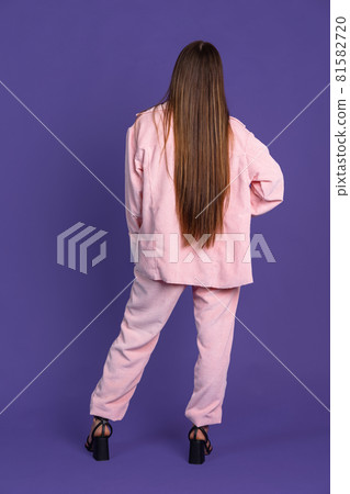 Rear view. Full-length portrait of young long-haired woman isolated on purple background 81582720