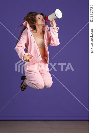 Full-length portrait of young emotional girl jumping over purple studio background 81582723