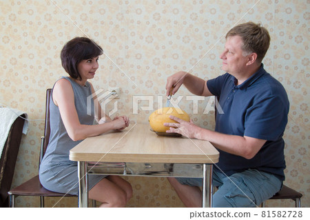 A man and a woman are cutting a melon at the table and discussing the past day A man and a woman are cutting a melon at the table and discussing the past day 81582728
