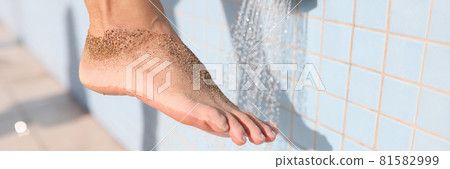 Woman washing her foot from sand under shower on beach closeup 81582999