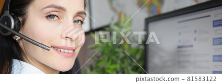Young woman in headphones with microphone sitting in front of computer screen 81583122