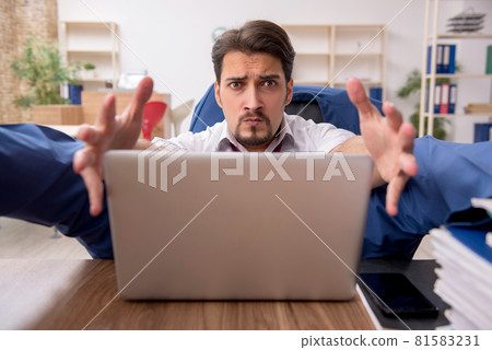Young male employee and too much work in the office 81583231