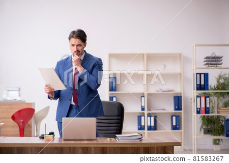 Young male employee sitting at workplace 81583267