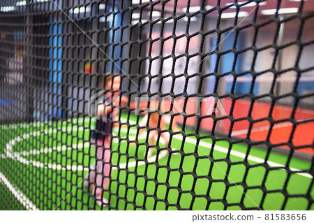 Blurred children are playing behind the net at indoor playground in activity park. 81583656