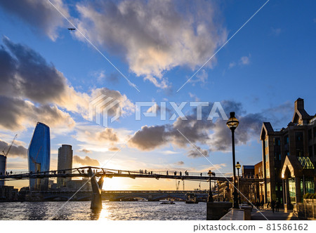 Sunset behind the Millennium Bridge in London, UK with dramatic clouds. It crosses the River Thames with Blackfriars Bridge and the South Bank behind 81586162