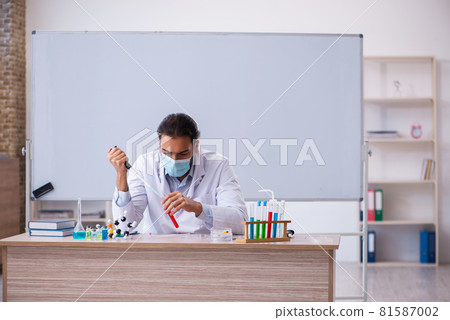 Young male chemist teacher sitting in the classroom Young male chemist teacher sitting in the classroom 81587002