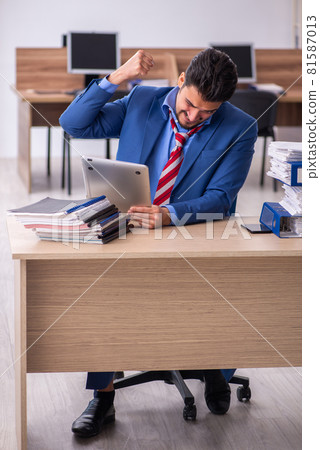 Young male employee unhappy with excessive work at workplace 81587013