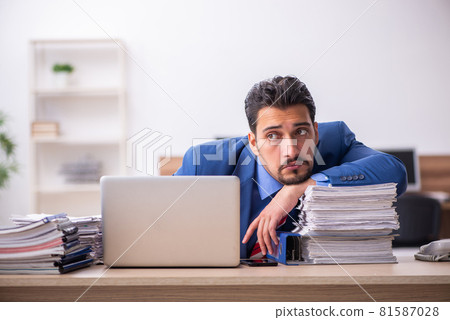 Young male employee unhappy with excessive work at workplace Young male employee unhappy with excessive work at workplace 81587028