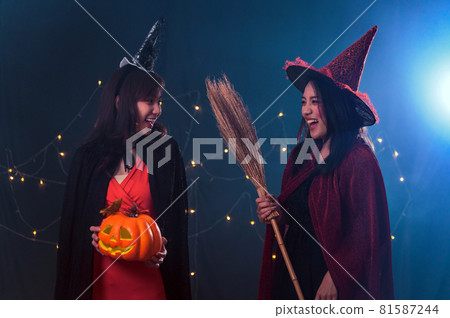 Portrait of two beautiful young woman in witch halloween costumes at party over dark magic background - Halloween party concept 81587244