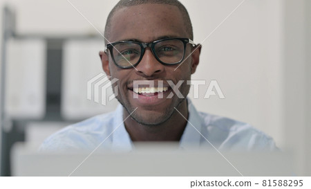 Close Up of African Man with Laptop Smiling at Camera 81588295