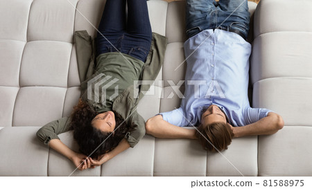 Happy positive young family couple relaxing on comfortable sofa. Happy positive young family couple relaxing on comfortable sofa. 81588975