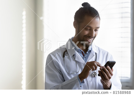 Smiling millennial african american doctor using smartphone application. 81588988