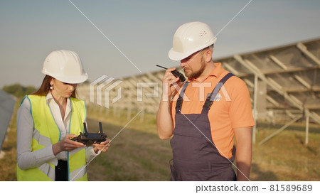 Portrait of a female engineer operating a drone on the background of a solar power plant. Photovoltaic solar panel installation. Solar array. New technologies. Investor and worker engineer 81589689