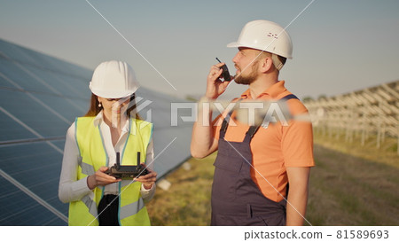Portrait of a female engineer operating a drone on the background of a solar power plant. Photovoltaic solar panel installation. Solar array. New technologies. Investor and worker engineer Portrait of a female engineer operating a drone on the background of a solar power plant. Photovoltaic solar panel installation. Solar array. New technologies. Investor and worker engineer 81589693
