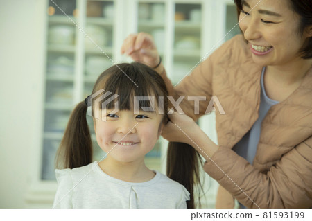 Mom tying child's hair 81593199