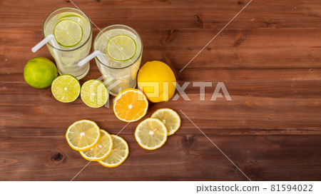 Two refreshing glasses of cold fruit juice with straw, ice lime and lemon juice, decorating with fresh lime and lemon on wooden table. Concept for refreshing Two refreshing glasses of cold fruit juice with straw, ice lime and lemon juice, decorating with fresh lime and lemon on wooden table. Concept for refreshing 81594022