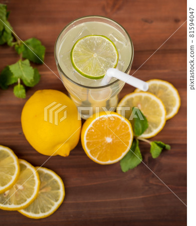 A refreshing glass of cold lime juice with ice and straw, decorating the glasses with lime slice. Fresh lime, lemon both cut and slice and mint leaf are on wooden table. Healthy concept A refreshing glass of cold lime juice with ice and straw, decorating the glasses with lime slice. Fresh lime, lemon both cut and slice and mint leaf are on wooden table. Healthy concept 81594047