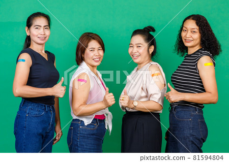 Four middle aged Asian women showing their arms with bandage patch showing they got vaccinated for Covid 19 virus on green background. Concept for Covid 19 vaccination 81594804