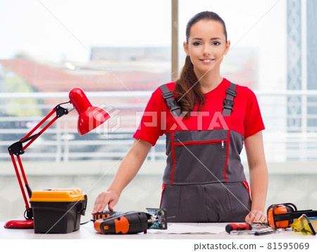 Young woman in coveralls doing repairs Young woman in coveralls doing repairs 81595069